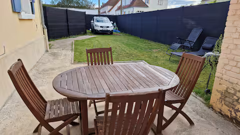 Le jardin clos de Dolce Vitta : table en bois, chaises et transats sur la pelouse